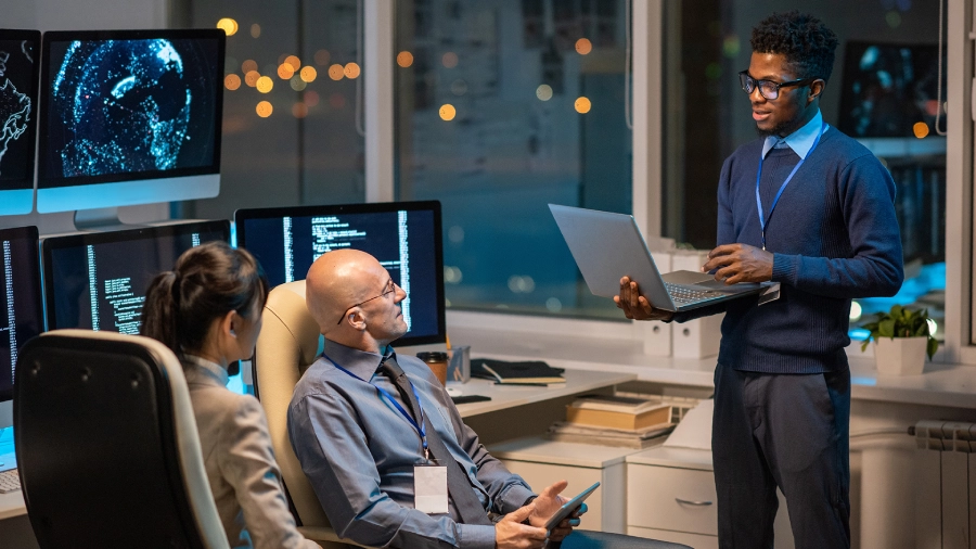 Young successful businessman with laptop making presentation for colleagues at working meeting in office